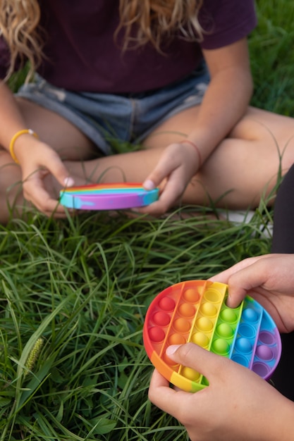 Meninas brincam de silicone colorido com toque popular de brinquedo pop-it ao ar livre na grama verde