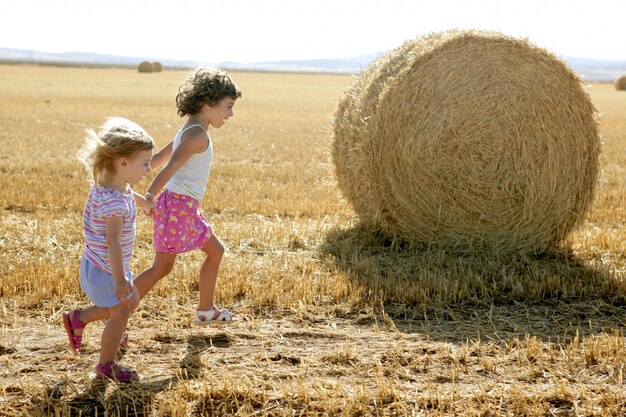 Meninas brincando com os fardos redondos de trigo