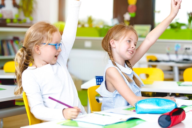 Meninas com as mãos levantadas na mesa na sala de aula