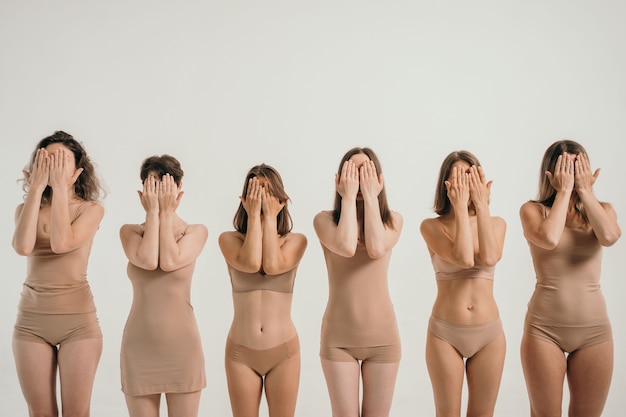 Foto meninas com diferentes figuras em cuecas bege as meninas cobrem seus rostos com as mãos um lugar ...