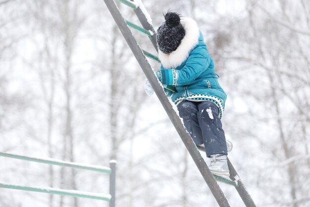 Meninas com jaquetas e chapéus quentes brincam em um parque de inverno com um cachorro passeando