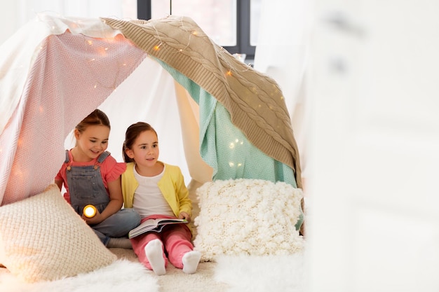 Foto meninas com livros e tochas na tenda das crianças em casa