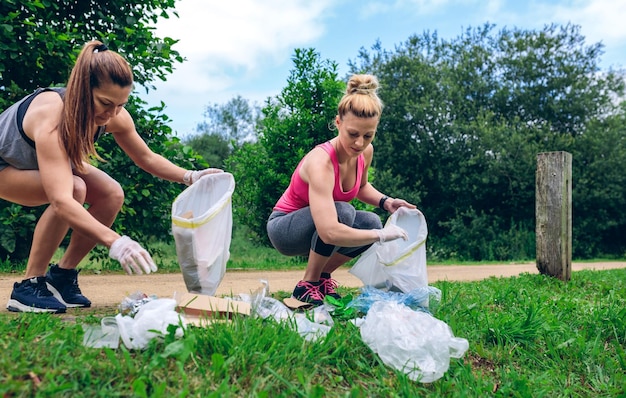 Meninas com saco de lixo fazendo plogging