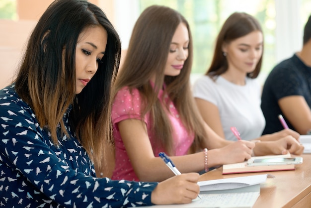 Meninas concentradas que estudam na universidade prepearing para exames.