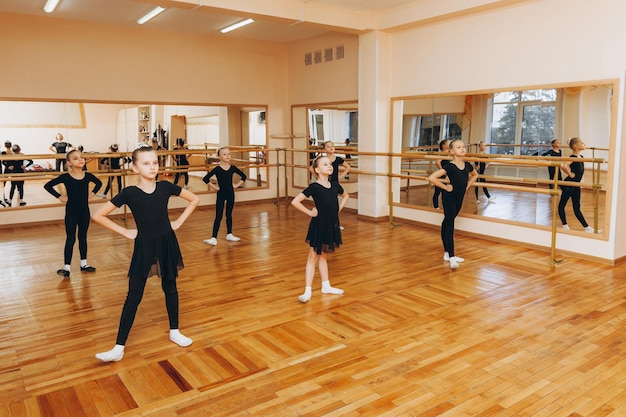 Meninas de 8 anos de terno preto estão fazendo coreografia em uma aula de balé.