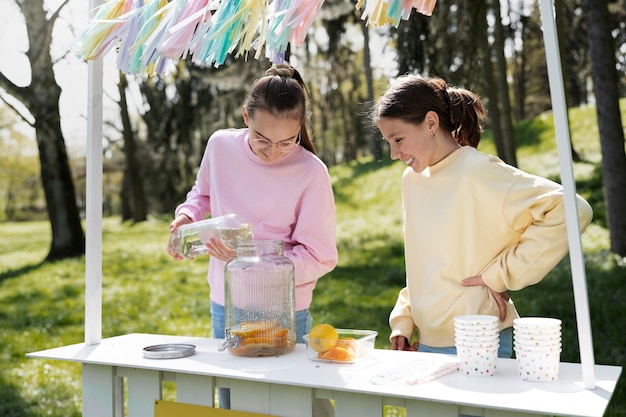 Meninas de tiro médio fazendo limonada juntos