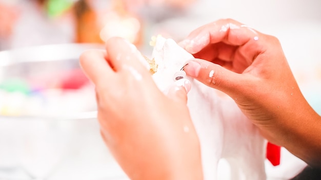 Meninas decorando unicórnio de papel machê com glitter e flores de papel.