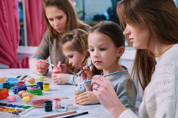 Meninas e mães pintando ovos de páscoa