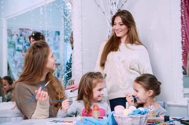 Meninas e mães pintando ovos de Páscoa