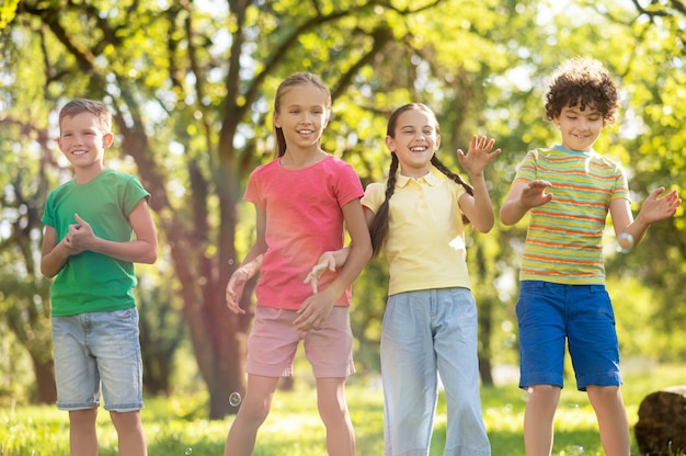 Meninas e meninos pegando bolhas de sabão