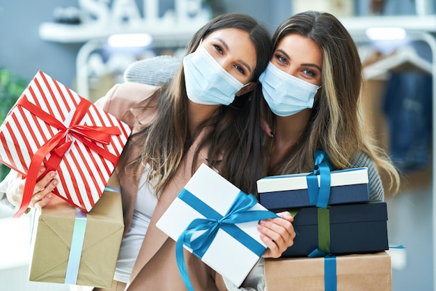 Meninas em compras na loja com roupas usando máscaras. Foto de alta qualidade