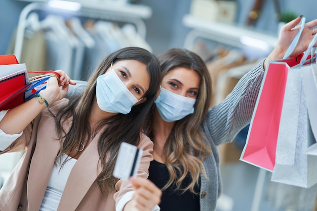 Meninas em compras na loja com roupas usando máscaras. Foto de alta qualidade