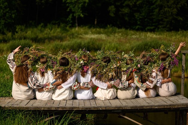 Meninas em coroas tecidas de várias flores e grama em um dia quente de verão Ivan Kupala feriado