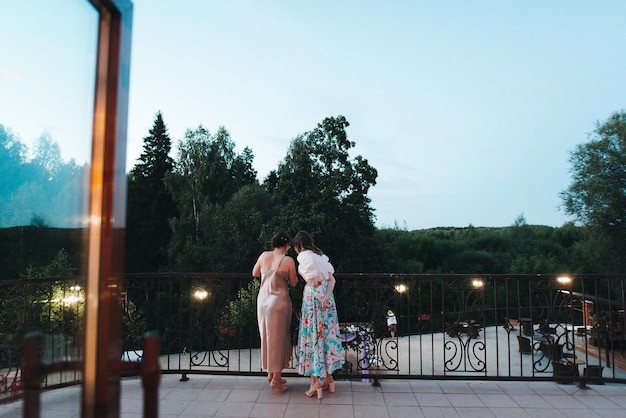 Meninas em lindos vestidos em pé na varanda do restaurante