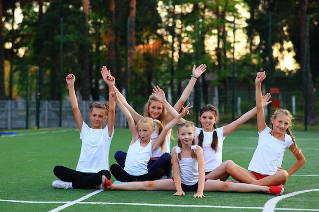 Foto meninas em roupas esportivas estão sentadas no parquinho.