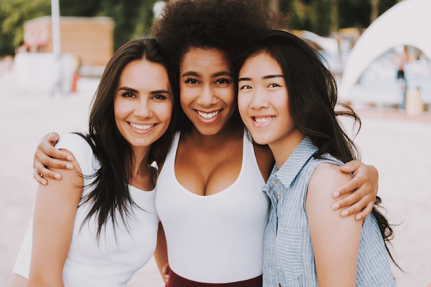 Meninas felizes abraçam amigos asiáticos caucasianos africanos