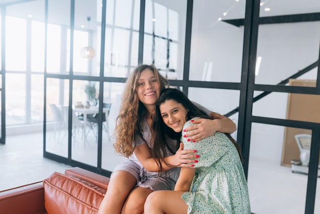 Meninas felizes abraçando em casa sentado em um sofá na sala de estar