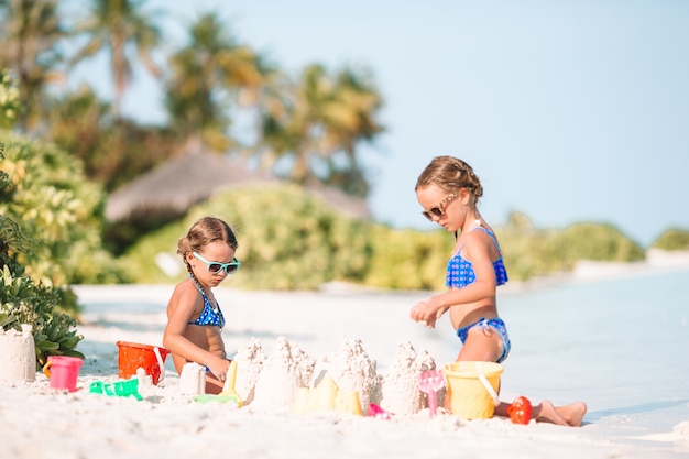 Meninas felizes brincando com brinquedos de praia durante as férias tropicais