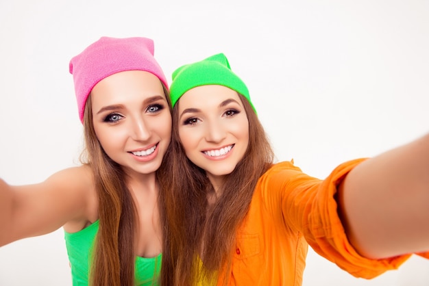 Meninas felizes e sorridentes com chapéus coloridos tirando selfie
