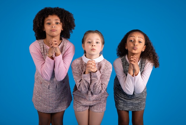 Meninas internacionais em gestos casuais para rezar, pergunte, olhe para a câmera isolada em azul