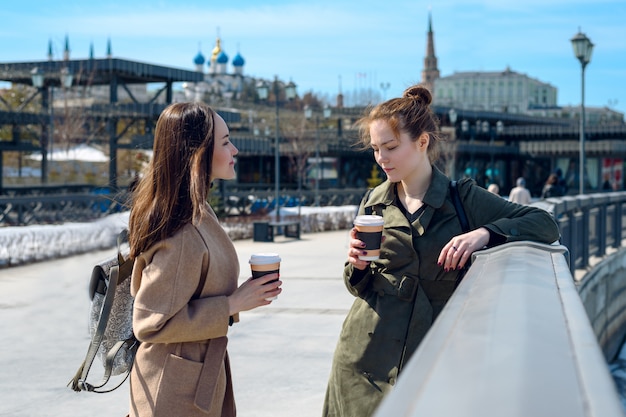 Meninas jovens em casacos e café conversando à beira-mar de Kazan. coffee-break