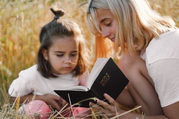 Meninas lendo a bíblia sagrada em um campo de trigo. estudem a bíblia sagrada juntos.