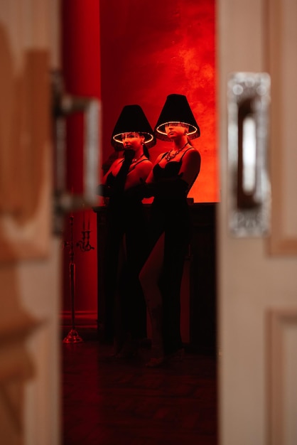 Meninas modelo em vestidos pretos com lâmpadas de assoalho iluminadas em suas cabeças