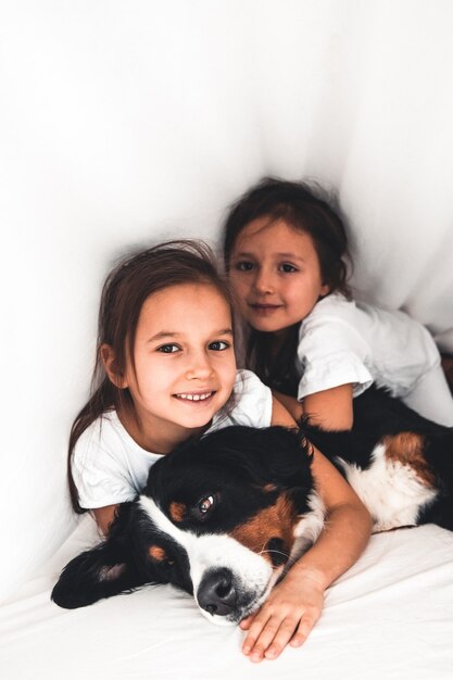 Meninas na cama com cachorro bernese mountain dog