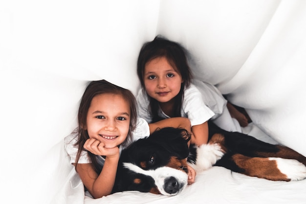 Meninas na cama com cachorro Bernese Mountain Dog