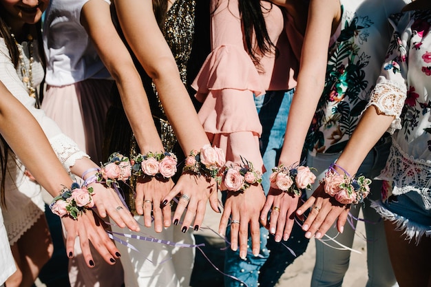 Meninas na praia mostram as mãos decorando flor na lapela com flores e fitas Casa de botão Estilo de festa boho Noite de solteira despedidas de solteira Close-up da aparência acima da vista superior