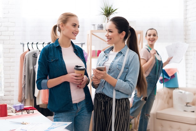 Meninas segurando café e telefone olham para o outro