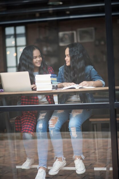 Foto meninas sorridentes estudando enquanto estão sentadas na mesa