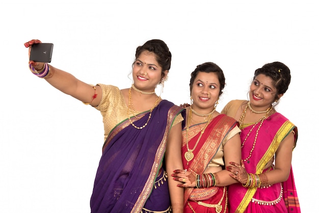 Meninas tradicionais indianas tomando selfie com smartphone em fundo branco