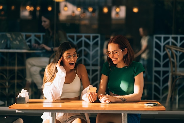 Meninas usando smartphones enquanto estão sentados no café ao ar livre