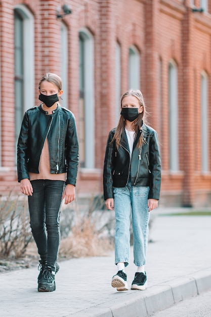 Meninas vestindo uma máscara em um fundo de um edifício moderno,
