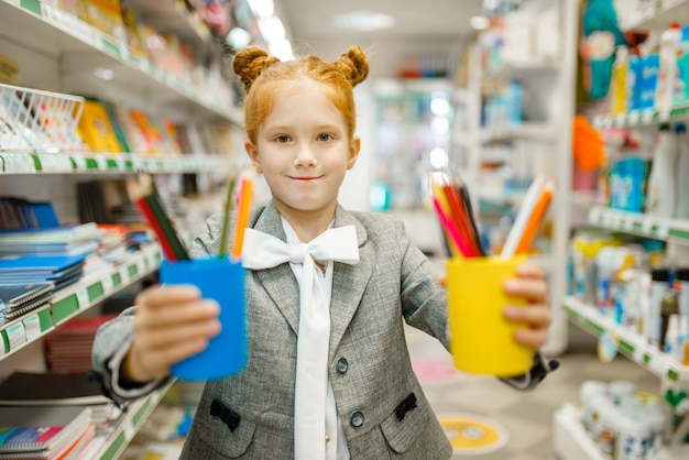 Menininha com lápis coloridos, comprando em papelaria