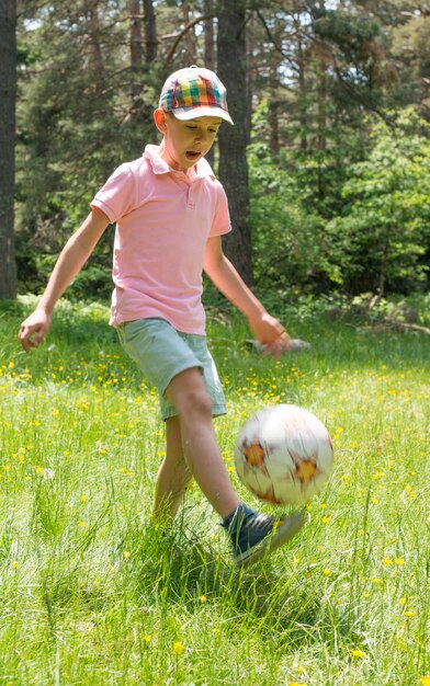 Menino a brincar com bola em terreno gramado