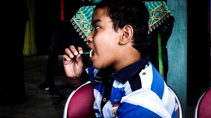 Foto menino a comer comida.
