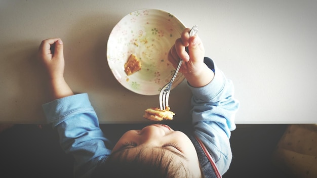 Foto menino a comer comida.