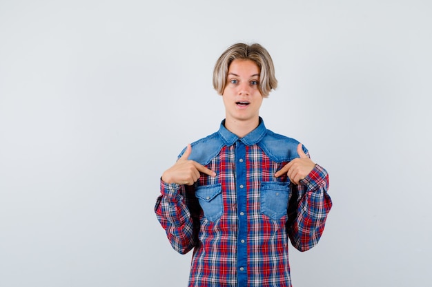 Foto menino adolescente apontando para si mesmo com uma camisa xadrez e parecendo surpreso