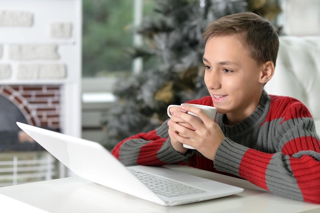Menino adolescente com laptop e xícara de chá