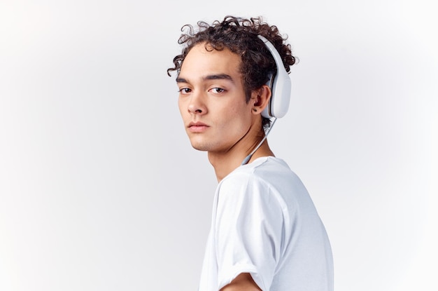 menino adolescente em uma camiseta ouvindo música em fones de ouvido em um fundo claro vista cortada close-up foto de alta qualidade