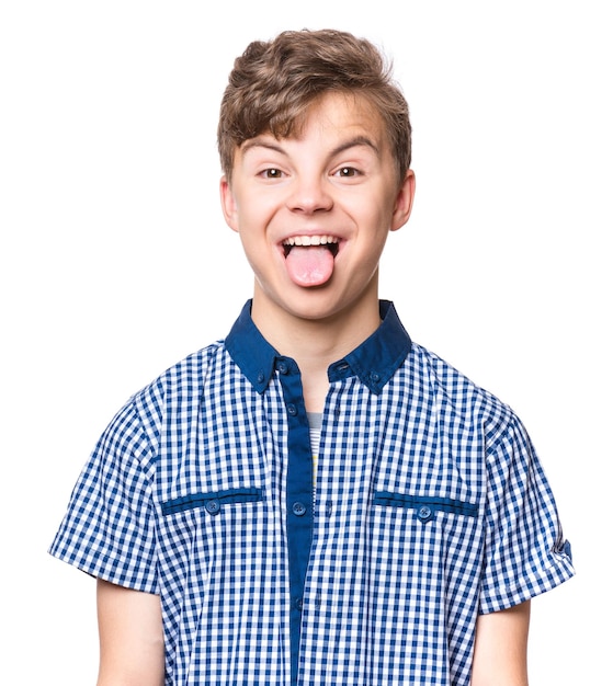 Foto menino adolescente engraçado mostrando sua língua isolado em fundo branco retrato emocional de adolescente caucasiano olhando para a câmera