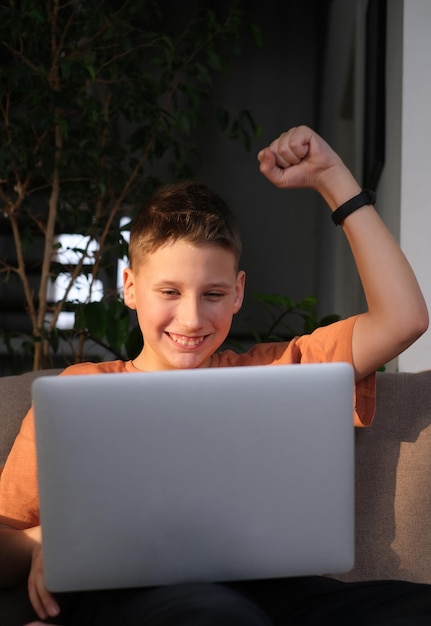 Menino adolescente estuda ou joga no fundo do interior da casa do laptop