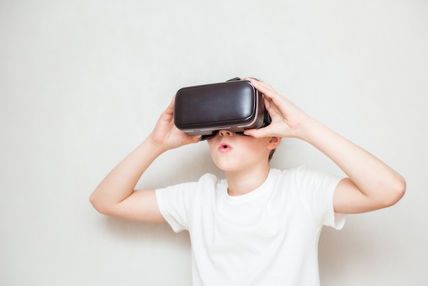 Menino adolescente feliz usando óculos de realidade virtual, assistindo a filmes ou jogando videogame, isolado no branco. Adolescente alegre olhando em óculos de Vr. Criança engraçada experimentando a tecnologia de gadget 3D