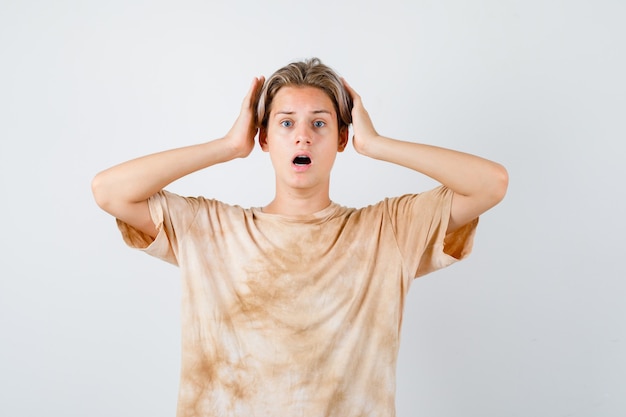 Menino adolescente mantendo as mãos perto da cabeça em t-shirt e parecendo desapontado. vista frontal.