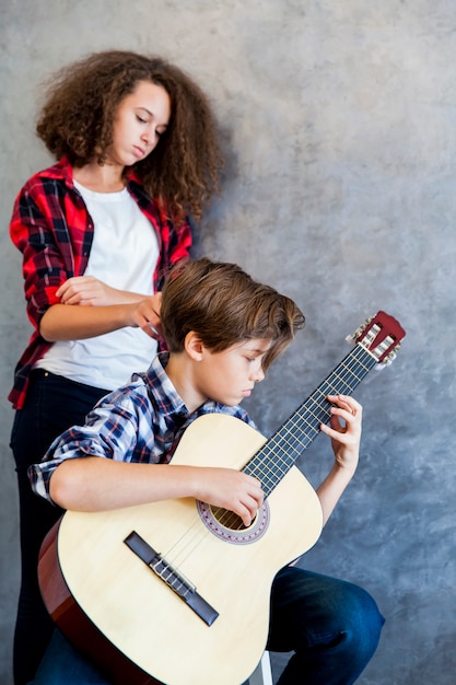 Foto menino adolescente, violão jogo, enquanto, menina adolescente, escutando, ele