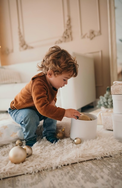 Foto menino adorável criança brincando com bolas de natal