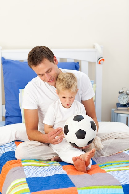 Menino adorável e seu pai brincando com uma bola de futebol