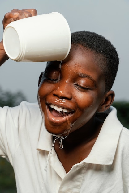 Foto menino africano sorridente lavando o rosto